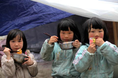 2013年4月22日，在四川省宝兴县临时安置点的帐篷前吃饭的孩子们