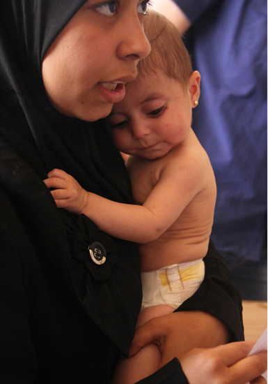 2014年11月，叙利亚，一位母亲怀抱着她的女儿。这个女婴正在联合国儿童基金会支持下的医疗中心接受营养不良的治疗。