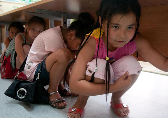 Fourth-graders seek shelter under a table during an earthquake preparedness exercise at a school in Kazakhstan. 